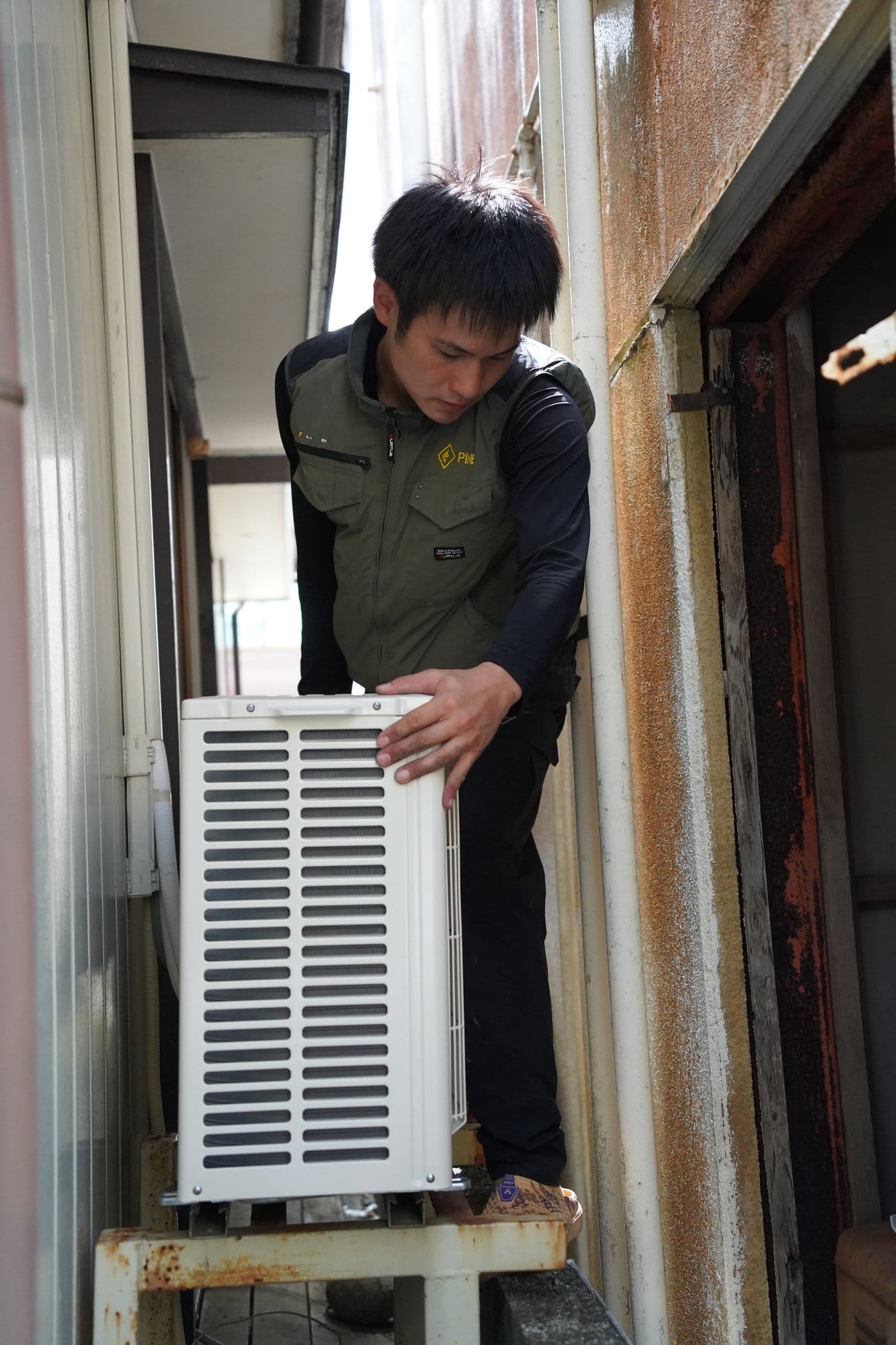 エアコンの室外機を運ぶスタッフ